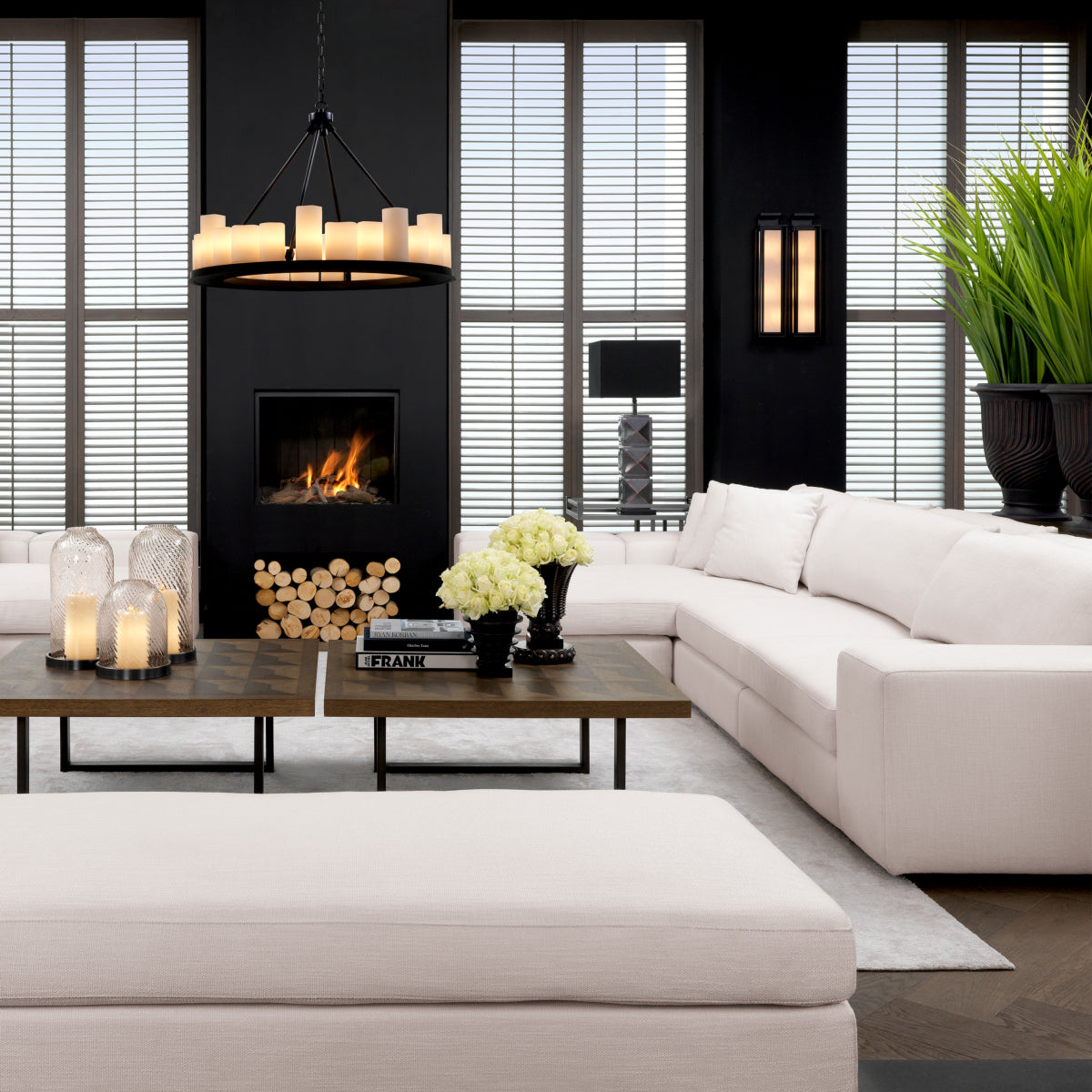 Modern living room with white L-shaped sofa, wooden coffee table, candles, and fireplace in a stylish interior.