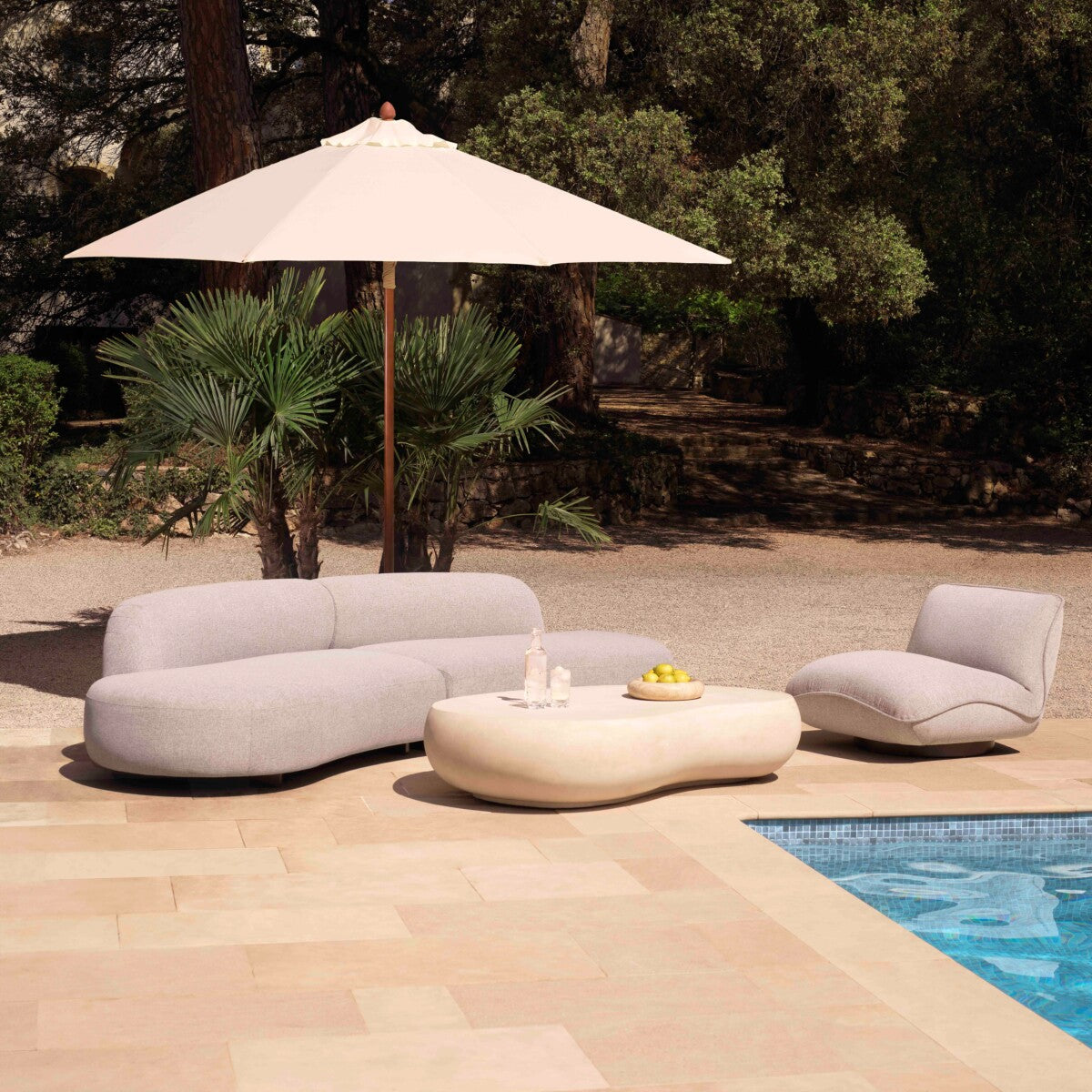 Bjorn Küçük outdoor garden sofa set with modern design, featuring light gray fabric near a pool and patio area.