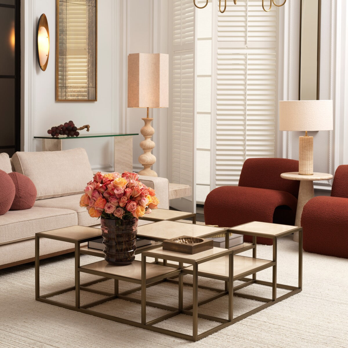 Modern living room with beige sofa, red armchairs, floral centerpiece, and stylish lamps.