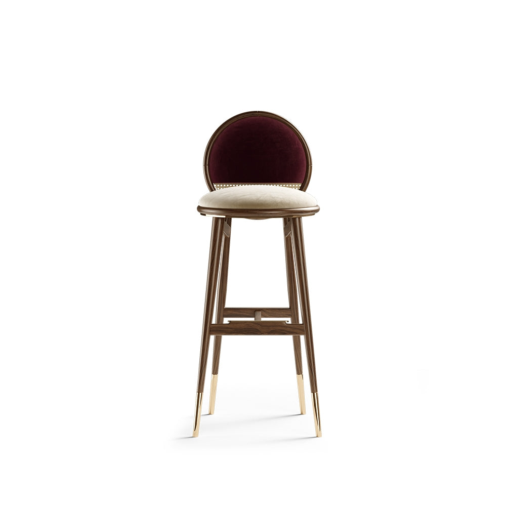 Dean bar stool with dark walnut wooden legs, brass feet, and plush fabric seat in burgundy color.