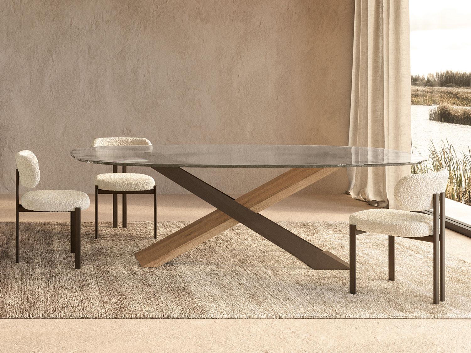 Modern round glass dining table with wooden X-shaped base and upholstered chairs in stylish interior setting.