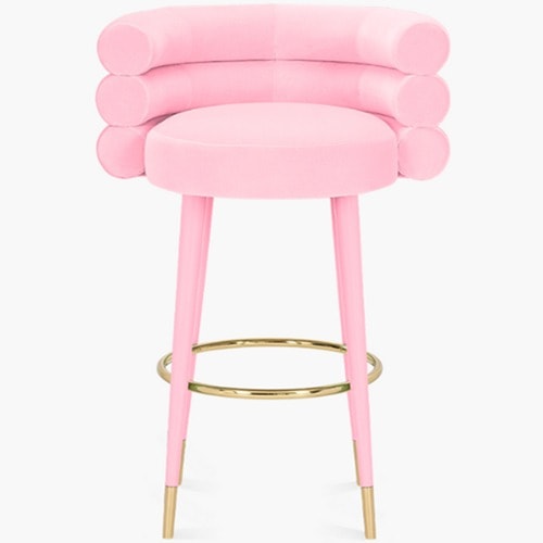 Marshmallow pink suede bar stool with rounded back, gold metal footrest, and wood legs, stylish and modern design.