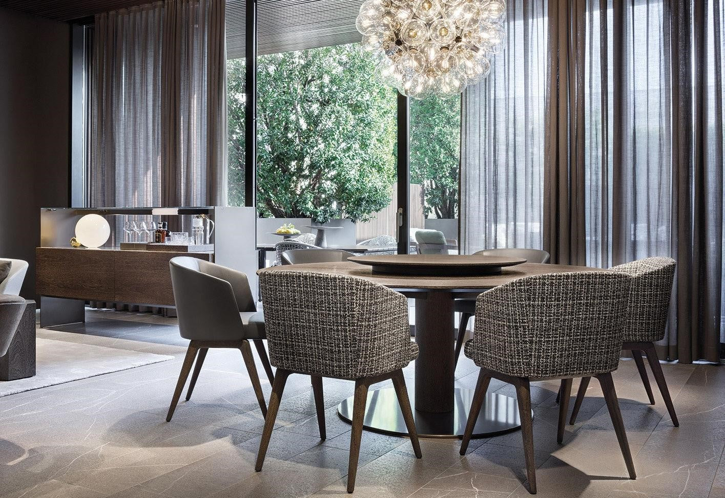 Modern dining room featuring Reeves textured brown linen upholstered walnut chairs around a sleek round table.