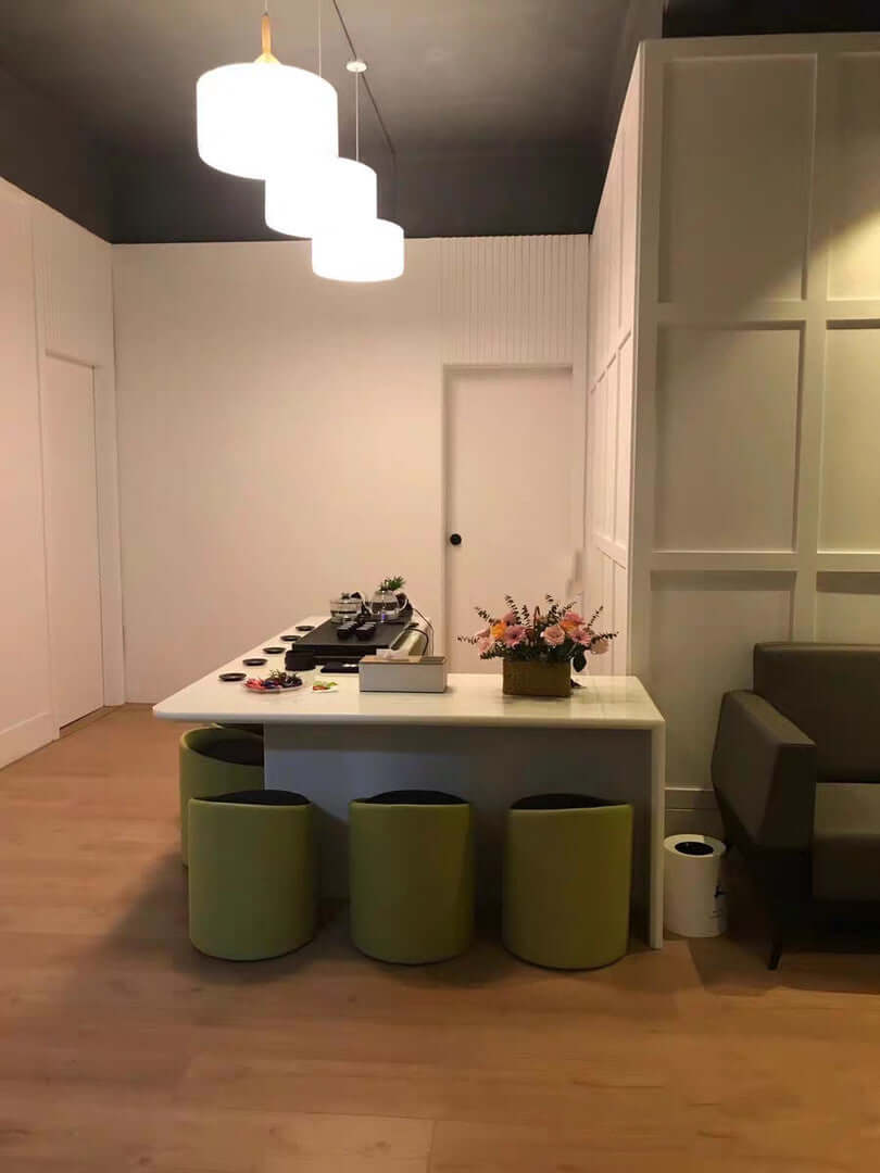 Modern interior design featuring a white table and green mini puffs in a chic office space.