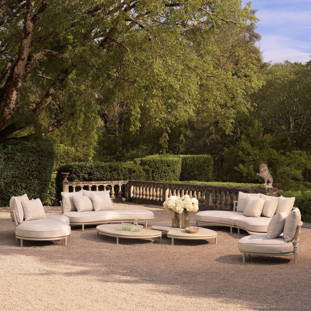 Laguno outdoor garden sofa set in beige, oval shape, with cushions, placed in a lush garden setting.