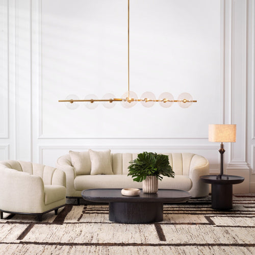Modern beige upholstered sofa with gold pendant light in an elegant living room setting.